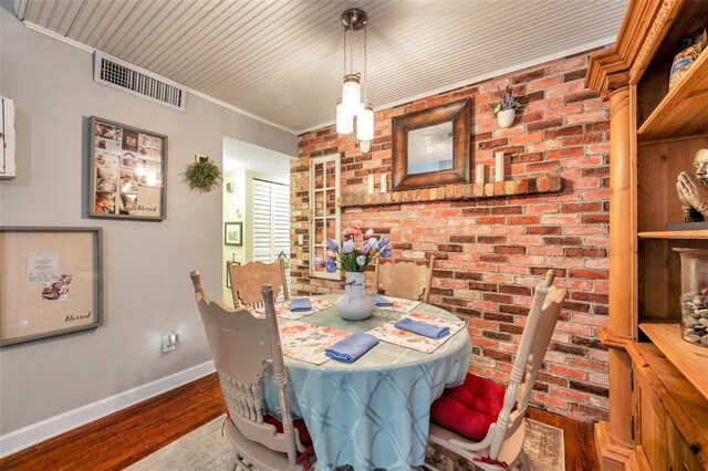 dining space with brick wall, ornamental molding, and hardwood / wood-style flooring