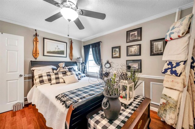 bedroom featuring a textured ceiling, ceiling fan, hardwood / wood-style floors, and crown molding