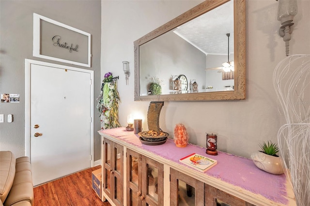 entrance foyer with dark hardwood / wood-style floors, vaulted ceiling, crown molding, and a textured ceiling