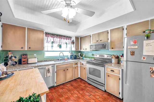 kitchen with sink, stainless steel appliances, ceiling fan, and a raised ceiling