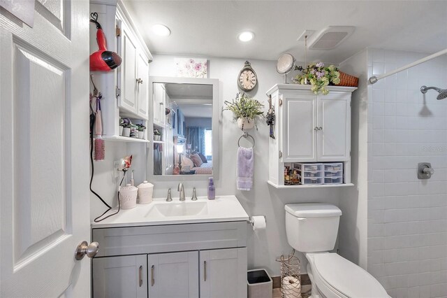 bathroom with tiled shower, toilet, and vanity