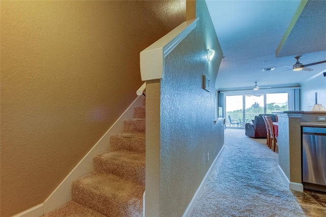 stairs with ceiling fan and carpet flooring