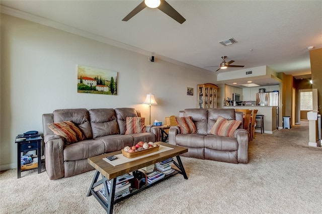 carpeted living room with crown molding and ceiling fan