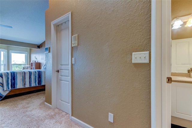 corridor with light carpet and sink