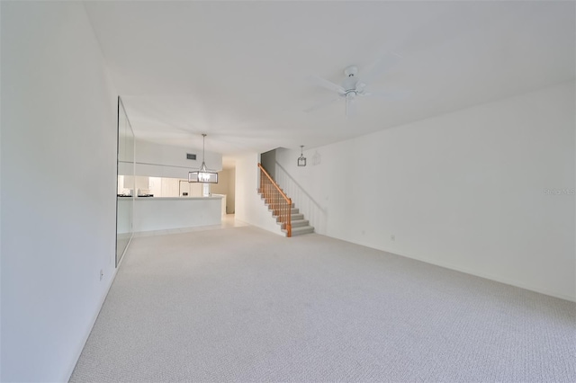 unfurnished living room with ceiling fan with notable chandelier and light carpet