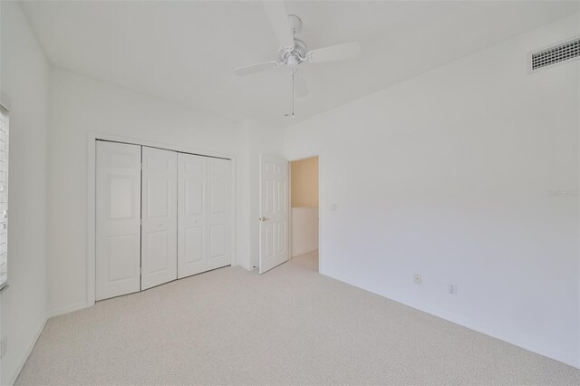 unfurnished bedroom featuring light colored carpet, ceiling fan, and a closet