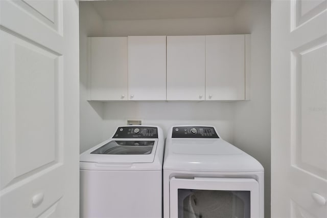 clothes washing area featuring cabinets and separate washer and dryer