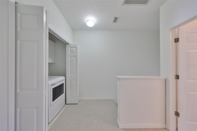 washroom with light colored carpet, washer / clothes dryer, and a textured ceiling