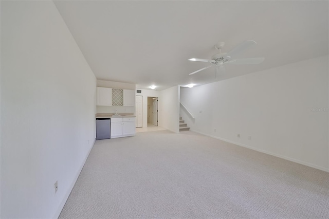 unfurnished living room featuring ceiling fan, sink, and light carpet