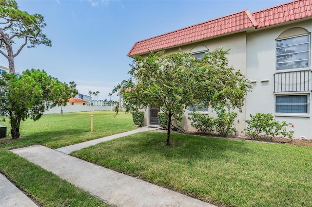 exterior space with stucco siding, a lawn, and a tiled roof