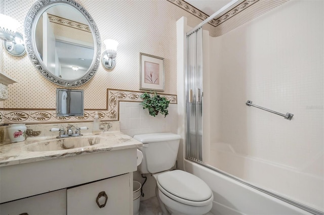 full bathroom featuring vanity, toilet, combined bath / shower with glass door, and tile walls