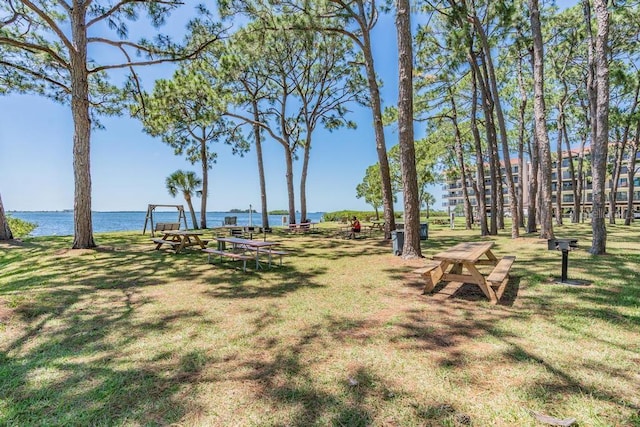 view of property's community with a water view and a lawn