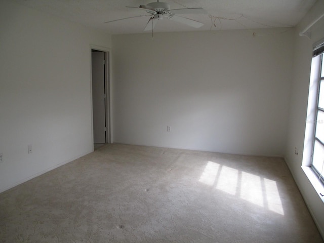 unfurnished room featuring ceiling fan, light colored carpet, and a healthy amount of sunlight