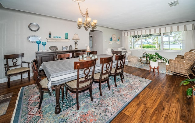 dining space featuring dark hardwood / wood-style floors and an inviting chandelier