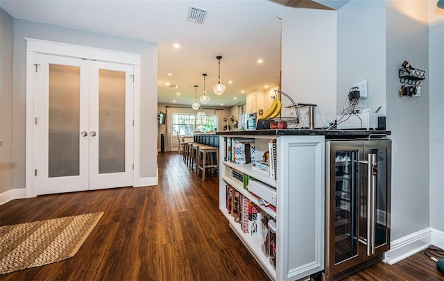 kitchen featuring white cabinets, french doors, dark hardwood / wood-style floors, wine cooler, and pendant lighting