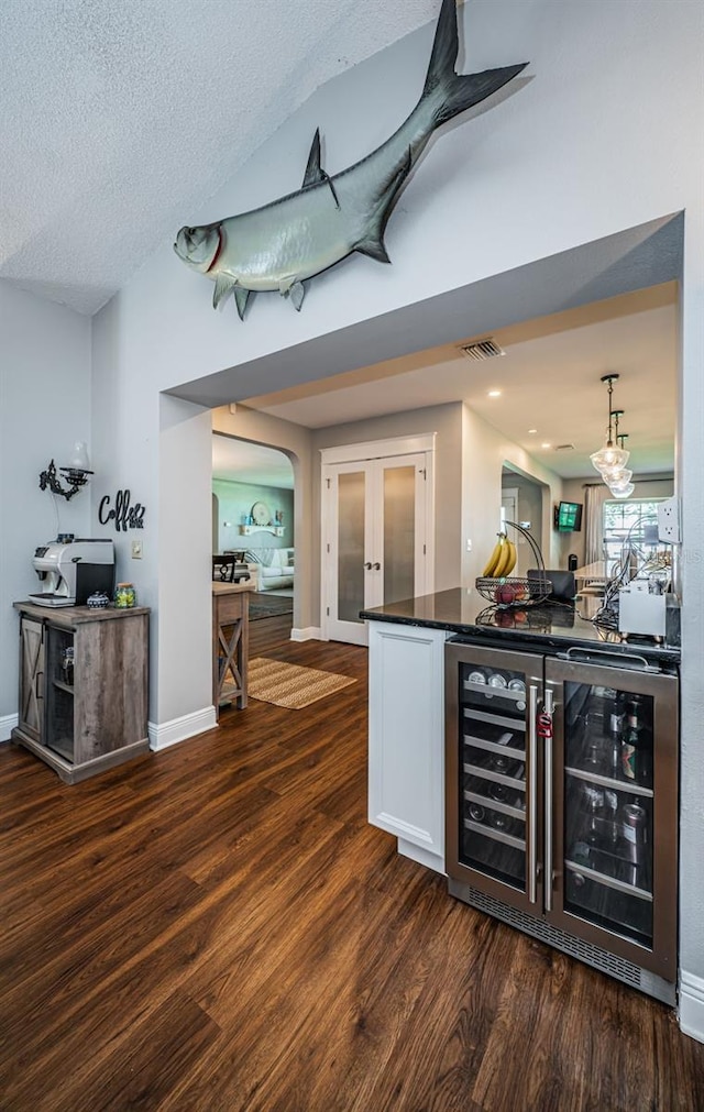 bar with a textured ceiling, wine cooler, pendant lighting, french doors, and dark wood-type flooring