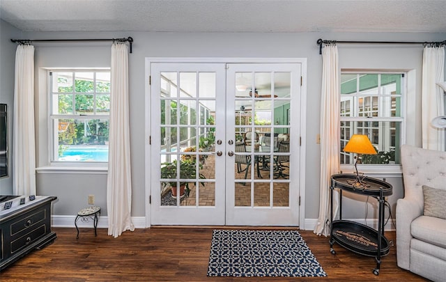 doorway with dark wood-type flooring, a textured ceiling, and french doors