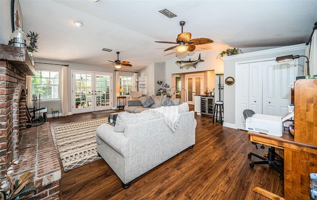 living room featuring a textured ceiling, a fireplace, dark wood-type flooring, lofted ceiling, and ceiling fan