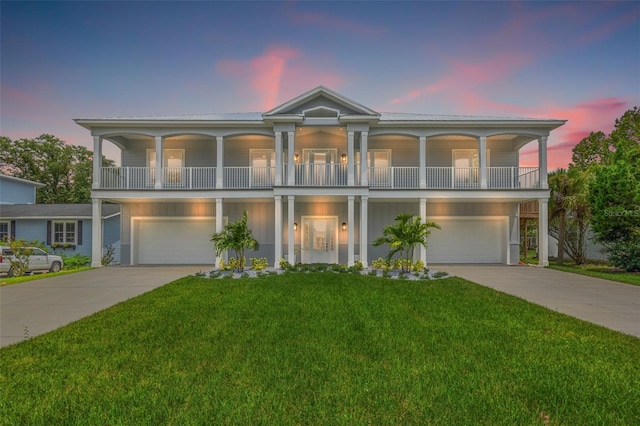 view of front of property featuring driveway, a balcony, an attached garage, and a yard