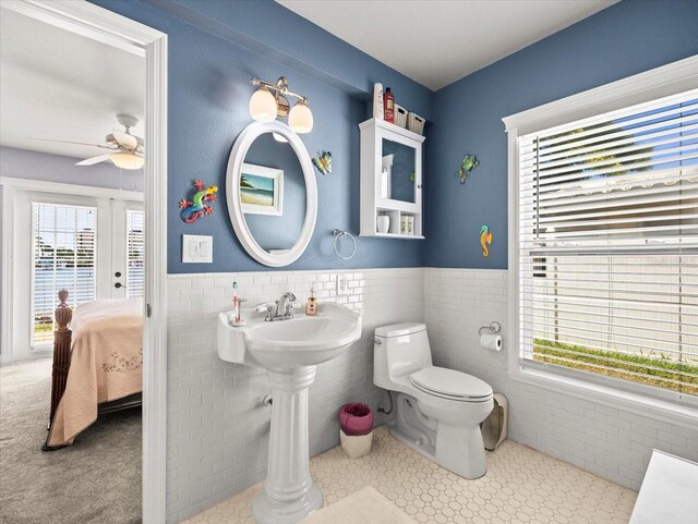 bathroom featuring tile walls and toilet