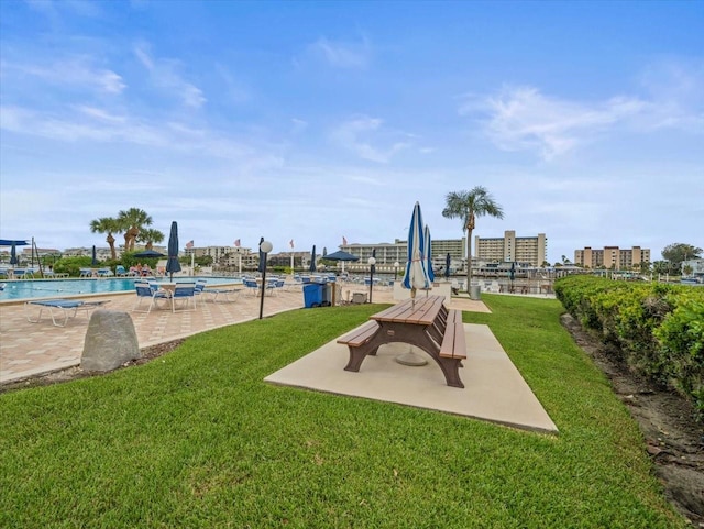 view of play area featuring a community pool, a patio area, and a lawn