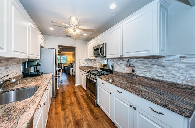 kitchen with backsplash, stainless steel appliances, white cabinetry, and dark hardwood / wood-style flooring