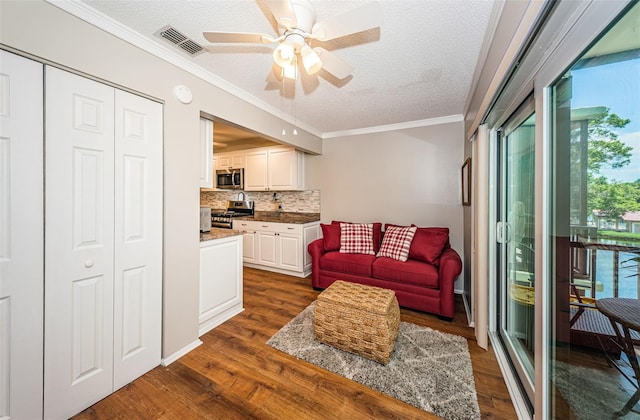 living room featuring a textured ceiling, ceiling fan, ornamental molding, and dark hardwood / wood-style floors