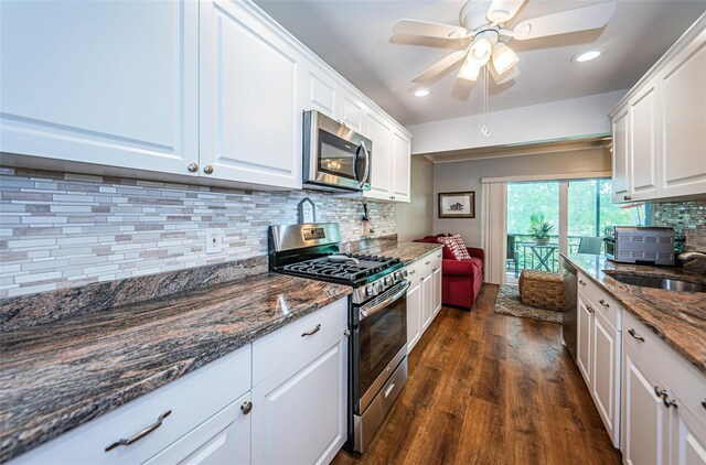 kitchen with appliances with stainless steel finishes, decorative backsplash, white cabinetry, dark hardwood / wood-style flooring, and ceiling fan