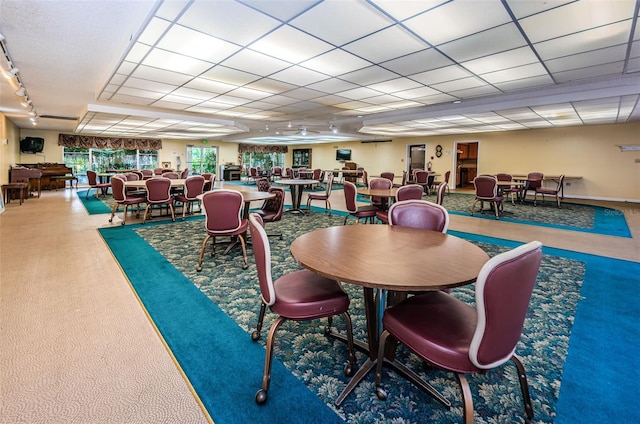 dining space with a paneled ceiling, rail lighting, and carpet floors