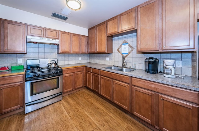 kitchen featuring sink, light wood-type flooring, backsplash, and gas stove