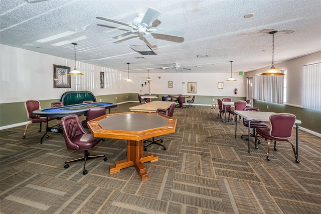 recreation room with a textured ceiling, dark colored carpet, and ceiling fan