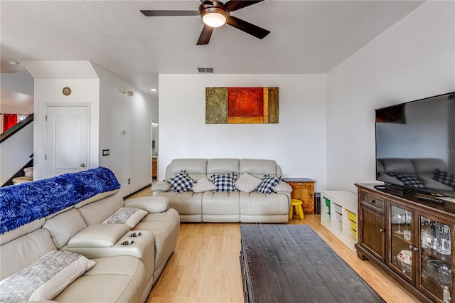 living room featuring ceiling fan, a textured ceiling, and light hardwood / wood-style floors