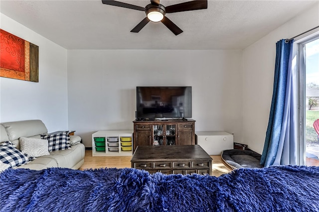 living room with ceiling fan, a textured ceiling, and wood-type flooring