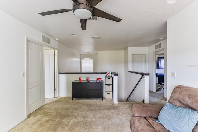 living room with a textured ceiling, ceiling fan, and light carpet