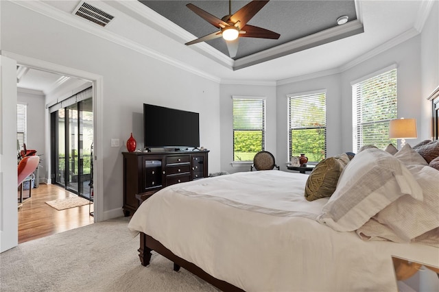 bedroom featuring ornamental molding, wood-type flooring, access to outside, a tray ceiling, and ceiling fan