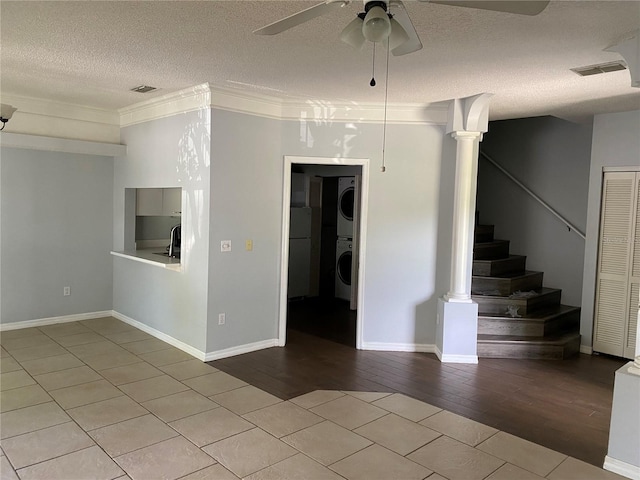 spare room featuring ceiling fan, light wood-type flooring, a textured ceiling, and stacked washer / dryer