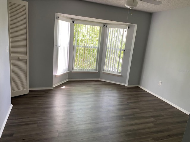 empty room with dark hardwood / wood-style flooring, ceiling fan, and a textured ceiling