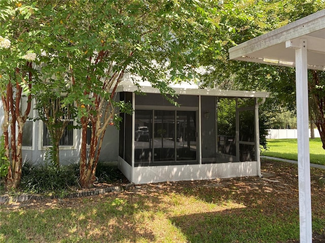 view of property exterior featuring a sunroom and a lawn