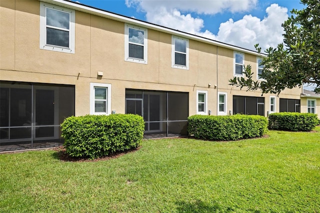 rear view of property featuring a sunroom and a lawn