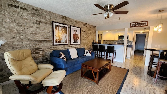 living room with a textured ceiling, brick wall, ceiling fan, and light hardwood / wood-style flooring