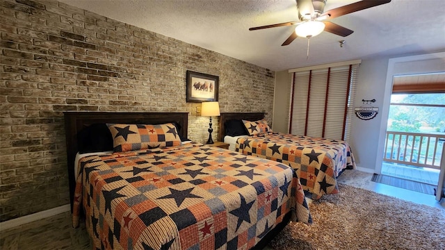 bedroom featuring a fireplace, a ceiling fan, a textured ceiling, brick wall, and baseboards