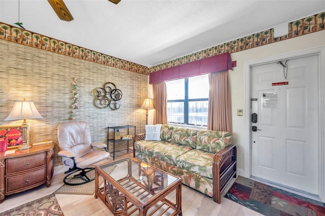 living room with a textured ceiling, ceiling fan, and light hardwood / wood-style floors