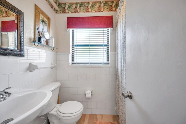 bathroom featuring toilet, backsplash, tile walls, wood-type flooring, and sink