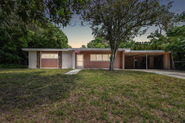 view of front of property with a lawn, concrete driveway, stone siding, an attached carport, and stucco siding