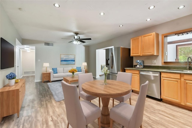 kitchen with appliances with stainless steel finishes, ceiling fan, sink, and light wood-type flooring