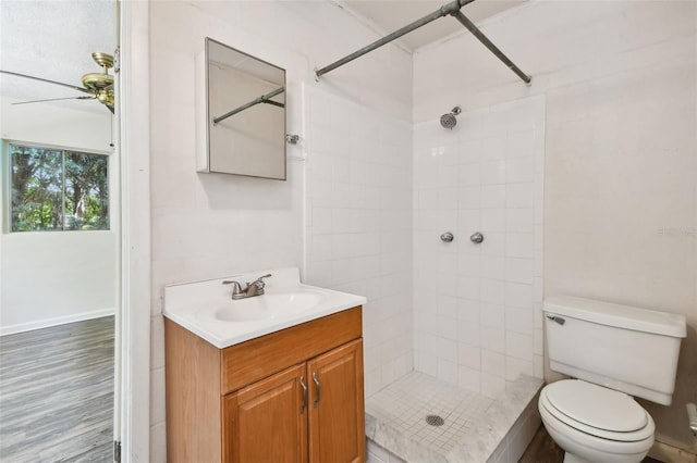 bathroom featuring a tile shower, vanity, hardwood / wood-style floors, and toilet