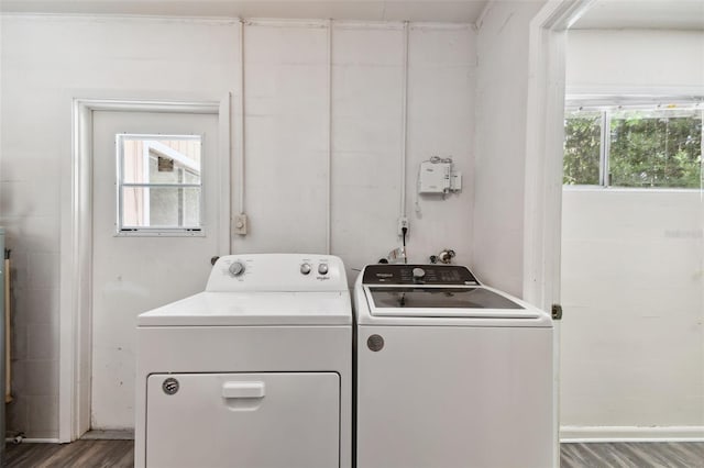 clothes washing area with separate washer and dryer, a wealth of natural light, and wood-type flooring