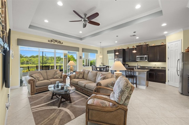 living room featuring ceiling fan, a tray ceiling, light tile patterned floors, and ornamental molding