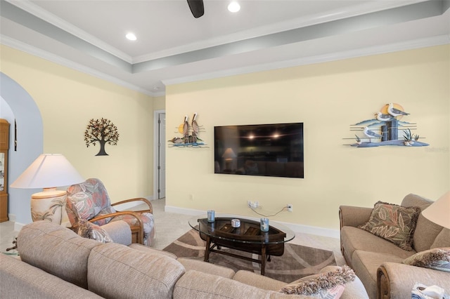 carpeted living room with ornamental molding and a tray ceiling