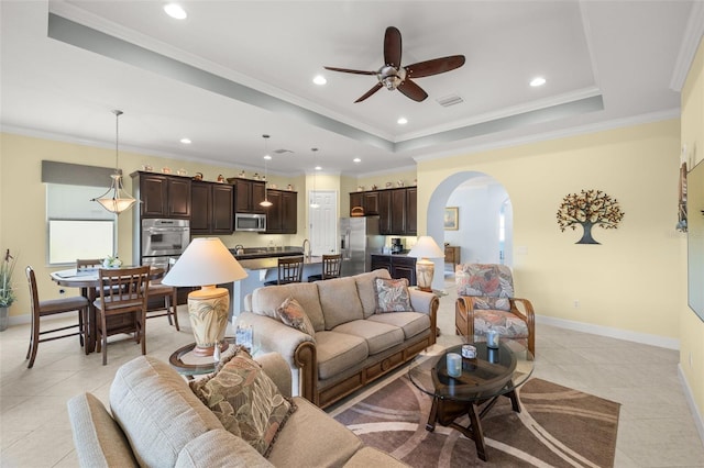 tiled living room with ceiling fan, crown molding, and a tray ceiling